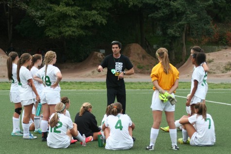 JV girls soccer team talking with coach during half time of their game.