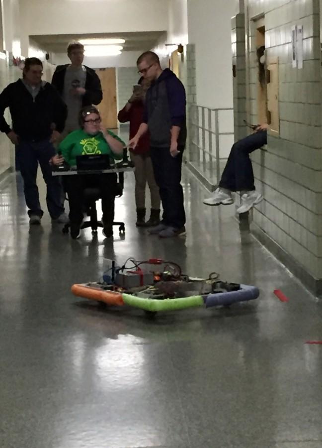 BraveBots 4682 takes  the finished chassis with omni wheels out for a test drive.  Johana Warrick is driving and Andrew Gilbrough is giving her instructions on how to drive. Mentor Dan Foley and team members Brendan Nenninger and Elise Valdez look after the robots responses.