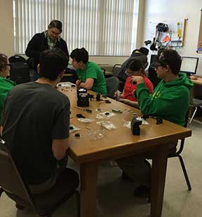 Mentor Dan Foley shows BraveBot team members Lorenzo Tamez, Annie Mae Foley, Cormac Brown, Will Marchand, and Johana Warrick how to set up motor gears.
