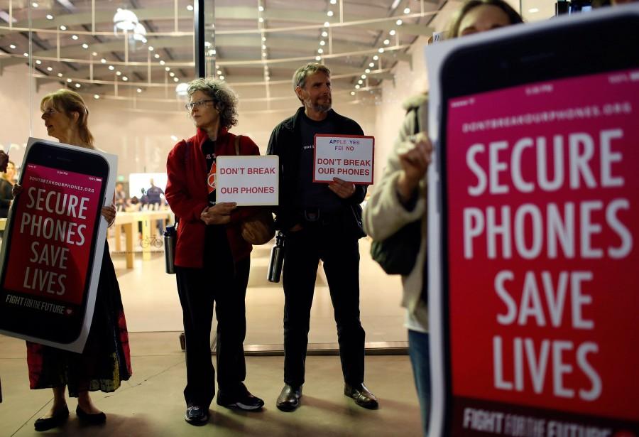 Protesters, from left, Sandra Bell, Victoria Best, and Charles Fredricks, hold signs in support of Apple store in Santa Monica, Calif., on Tuesday, Feb. 23, 2016.