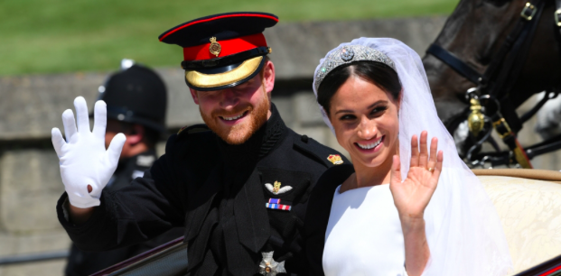 Meghan+Markle+and+Prince+Harry+smile+and+wave+to+the+large+crowd+that+gathered+outside+the+chapel+as+they+embark+in+a+horse-drawn+carriage+to+their+wedding+reception.