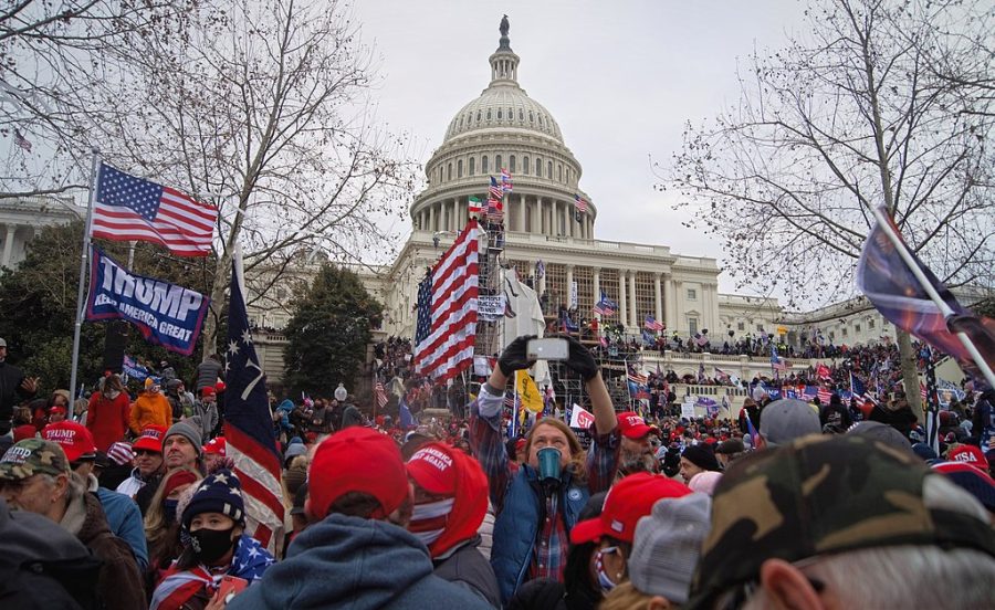 Rioters outside the US Capitol building holding US flags and "Make America Great Again" flags.