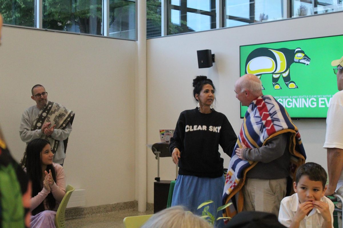 WRAPPED IN RESPECT: After signing the MOU, Sarah, a representative from Clear Sky who has been working with Blanchet for years, rewards Mr. McFeron and President DiSapio by wrapping them in blankets. This practice is seen as a sign of respect in many Indigenous cultures.